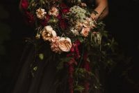 a moody Halloween wedding bouquet with burgundy and blush blooms, lots of greenery and cascading foliage