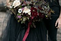 a moody Halloween wedding bouquet with burgundy blooms, neutral ones, greenery and grasses is chic