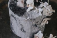 a moody grey wedding cake with black glitter, white blooms on top for a chic touch