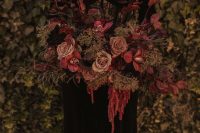 a moody wedding bouquet of dusty pink, burgundy and pink blooms, dark foliage, moss and greenery for Halloween