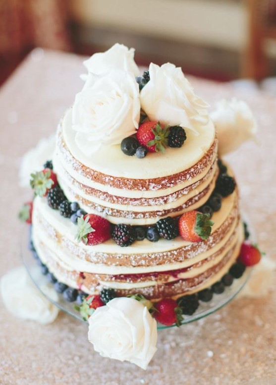 a mouth watering naked wedding cake with white blooms and fresh berries is a lovely dessert for a rustic wedding