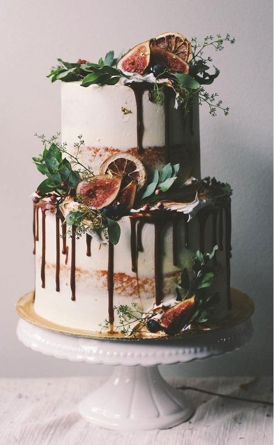 a naked two-tier wedding cake with chocolate drip, greenery, citrus slices, fresh berries and figs is a lovely idea
