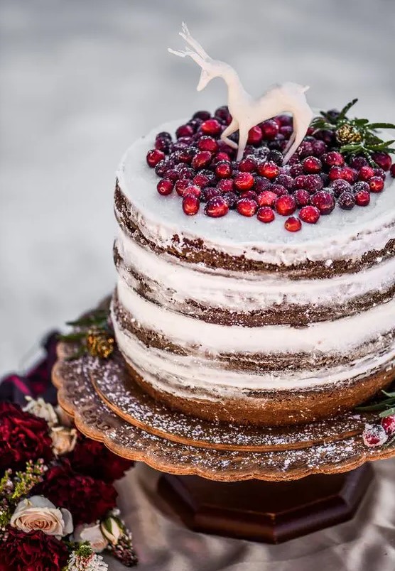 a naked wedding cake topped with fresh cranberry and a sugar deer is a gorgeous option for Christmas