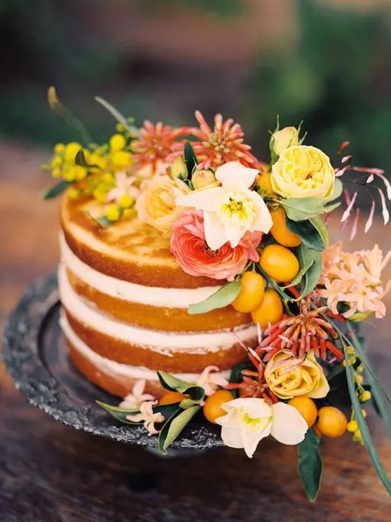 a naked wedding cake topped with yellow, pink and white blooms and kumquats for a Mediterranean wedding