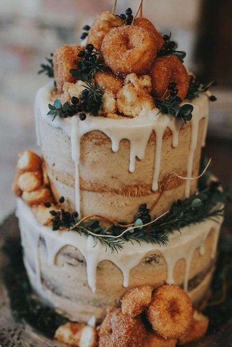 a naked wedding cake with creamy drip, greenery, berries and apple cider donuts for a fall rustic wedding