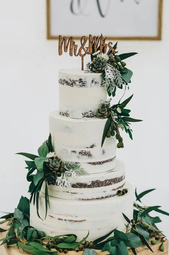 a naked wedding cake with greenery, succulents, berries, pale greenery, a wooden topper for a rustic wedding