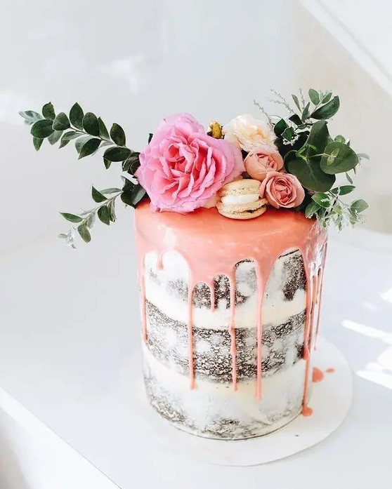 a naked wedding cake with pink drip, vanilla macarons, fresh blooms and foliage