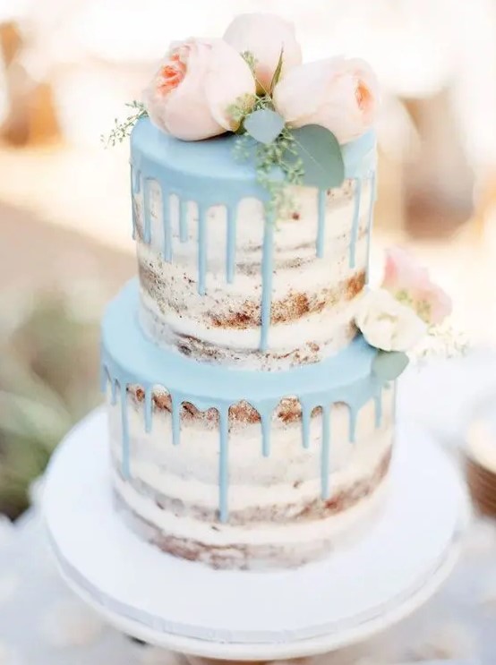 a naked wedding cake with powder blue drip and blush peonies looks very spring-like