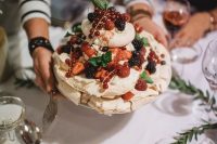 a pavlova wedding cake topped with fresh berries, mint and some dip is a very tasty idea to enjoy