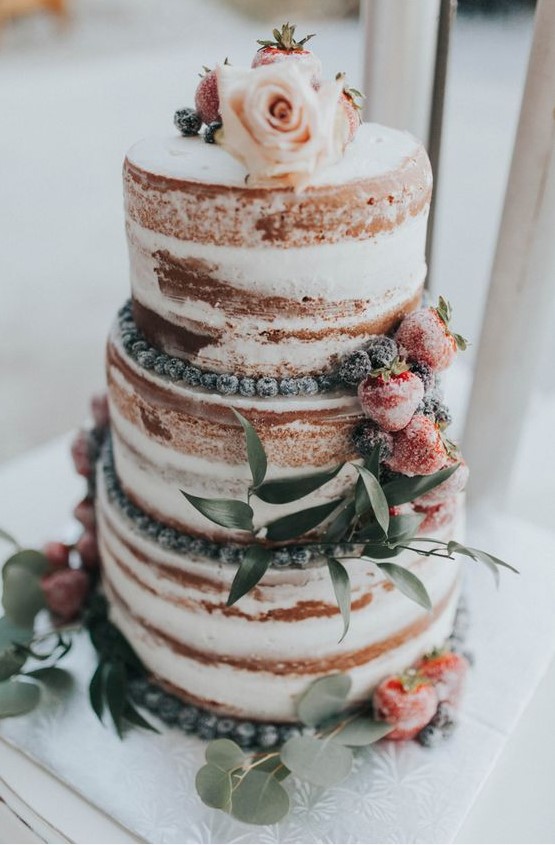 a romantic naked wedding cake with sugared berries, blush blooms and foliage is a gorgeous dessert for a spring or summer wedding