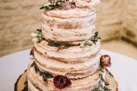 a rustic naked wedding cake with pink and purple blooms and greenery and a wire topper is a yummy piece