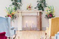 a shabby chic mantel with colroful candles, greenery and floral arrangements and colorful vintage chairs