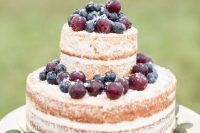 a simple and cool naked wedding cake topped with fresh blueberries and grapes is a great idea for a fall vineyard wedding