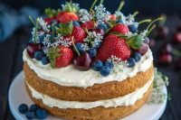 a sponge naked wedding cake with whipped cream, fresh flowers and berries – serve several ones for the guests