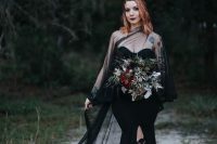 a statement Halloween bridal look with a strapless black mermaid wedding dress with a front slit and a sheer tulle coverup