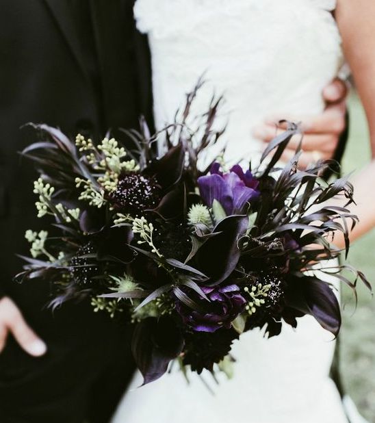 a statement Halloween wedding bouquet with bright and deep purple blooms, greenery, privet berries and foliage