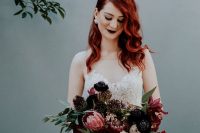 a statement dark wedding bouquet of black and burgundy blooms and some greenery for a Halloween wedding