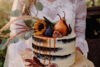 a statement fall naked wedding cake of chocolate, with pears, figs, greenery and blooms on top and some caramel drip