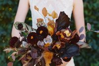 a statement moody wedding bouquet with deep purple, orange and lavender blooms, dark foliage and dark ribbons