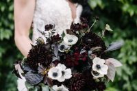a striking Halloween wedding bouquet with white and deep purple blooms, greenery and dark foliage plus cascading elements