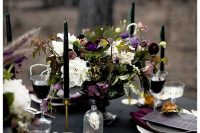 a stunning Halloween wedding centerpiece of white, purple and deep burgundy blooms and greenery plus thin and tall candles