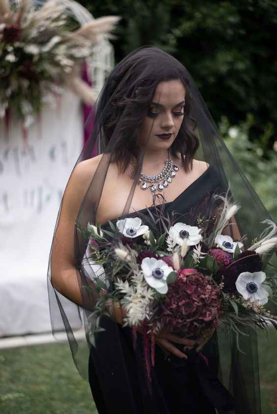 a stylish Halloween wedding bouquet with white and burgundy blooms, greenery and grasses for a modern Halloween bride