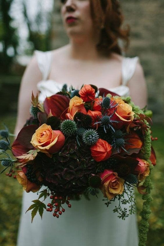 a stylish dark Halloween bouquet with burgundy, orange and red blooms, deep purple flowers, berries, thistles and eucalyptus
