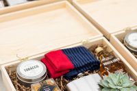 a stylish groomsmen box with socks, a succulent, a flask, a mini alcohol bottle, some snacks, tobacco and matches