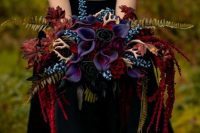 a super bold Halloween wedding bouquet with burgundy, blue and deep purple blooms, red cascading ones, ferns and mini antlers
