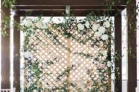 a trellis wall with lots of greenery, white hydrangeas and much foliage on the floor is very fresh and romantic
