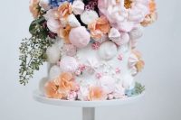 a white wedding cake decorated with pink and white meringue kisses, stars and roses and lots of beautiful pastel blooms