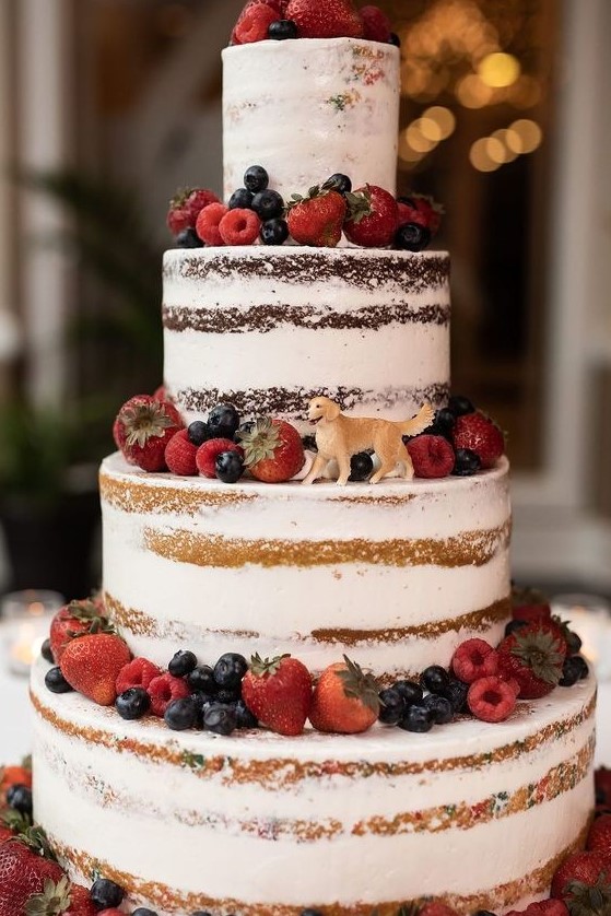 a yummy looking naked four tier wedding cake topped with fresh berries and with a sugar dog topper is a fantastic idea