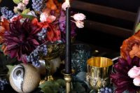 bold and catchy wedding centerpiece of colorful blooms, berries, black candles and larrge eyeballs are scary yet stylish