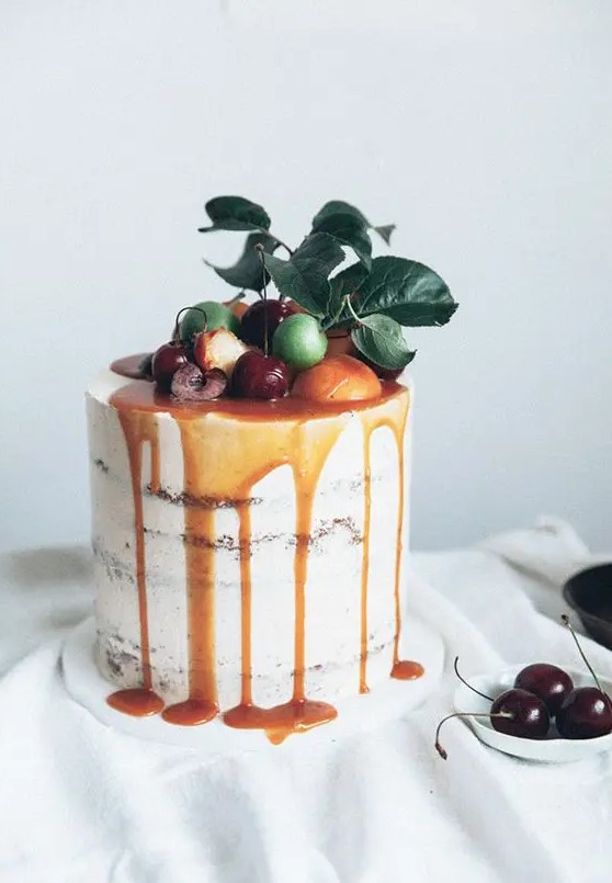 caramel drizzle semi naked wedding cake topped with citrus, cherries and fresh leaves for a summer wedding