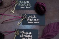 elegant matte black escort cards with gold calligraphy, vintage brass keys and moody blooms