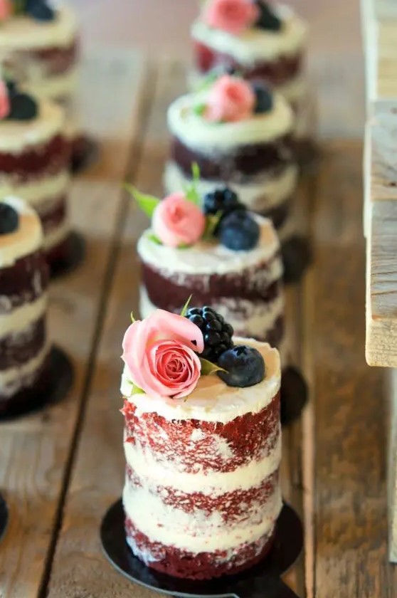 individual naked wedding cakes with a bit of buttercream on top, blueberries, blackberries and roses