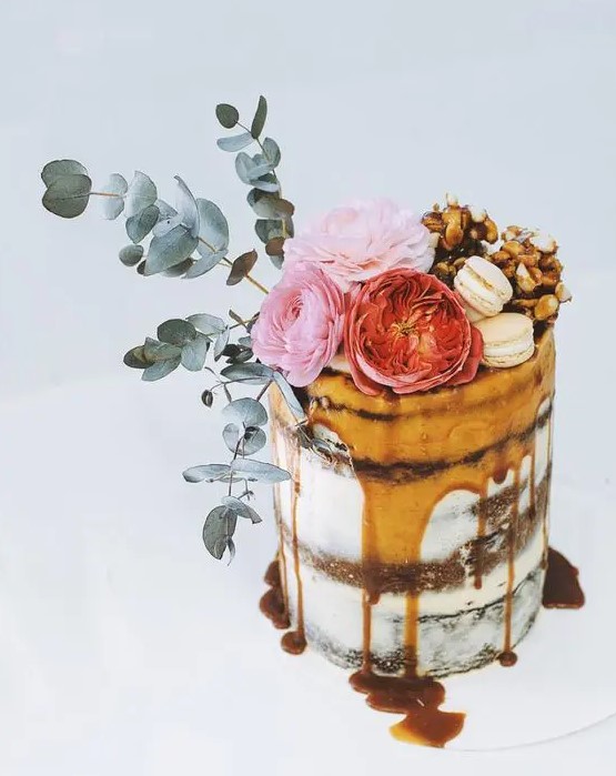 layers of salted caramel, chocolate brownie and raspberry flourless cake topped with flowers and greenery