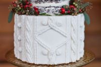 a Christmas wedding cake with a naked part and a cable knit one plus berries and little pinecones around