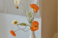 a beauitful and delicate wedding centerpiece of a white polka dot vase, white and orange poppies is a great idea for spring or summer