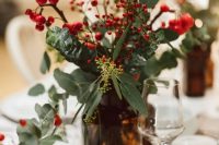 a beautiful Christmas wedding centerpiece of an apothecary bottle, greenery, berries looks very festive and cozy