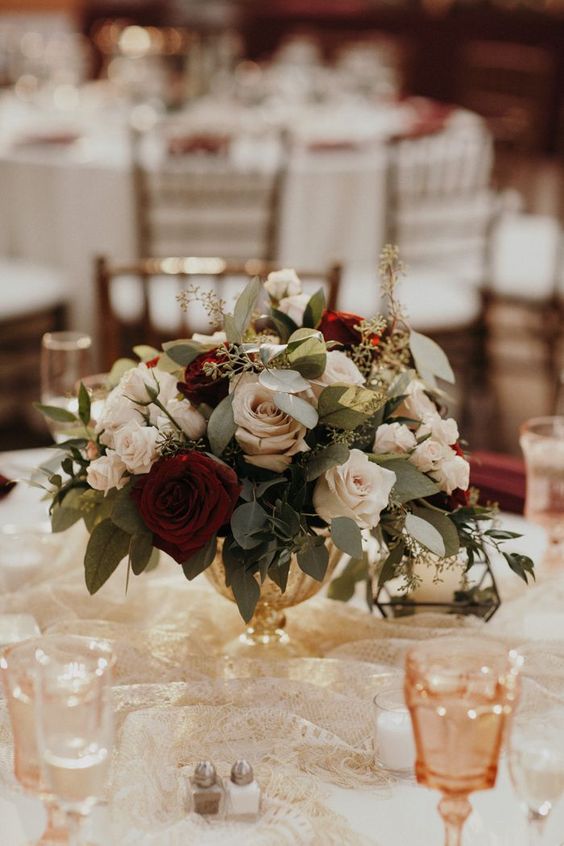 a beautiful floral Christmas wedding centerpiece of a gold bowl, white, lilac and brugundy blooms and eucalyptus will always work