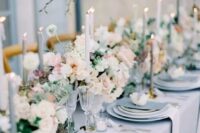 a beautiful pale blue spring wedding table setting with pale blue linens, candles and menus, neutral and pastel blooms and greenery