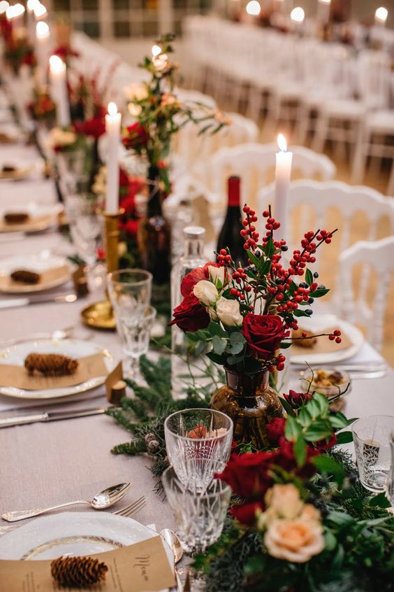 a beautiful rustic Christmas wedding centerpiece of greenery, white and red blooms, berries and fir branches