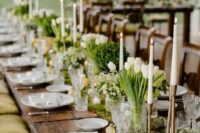 a beautiful secret garden wedding table with a moss runner, white blooms and greenery, lemons, tall candles and white plates