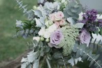 a beautiful wedding centerpiece of purple, lavender, blush and white blooms and with lots of greenery from mint to darker greens