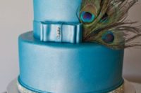 a blue wedding cake decorated with rhinestones and peacock feathers is a very creative and bold idea