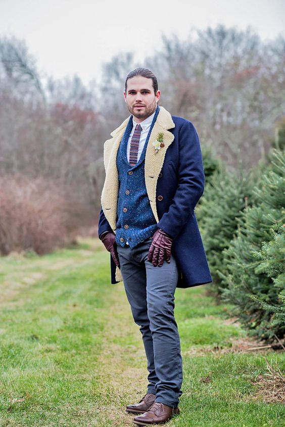 a boho winter groom's outfit with a white button down, a striped tie, a blue cardigan, grey pants, brown shoes and a blue coat with faux fur
