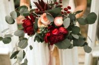 a bold Christmas wedding bouquet of red, blush and peachy blooms and lots of cascading greenery