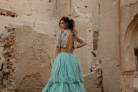 a bold bridal look with a crop embellished top with short sleeves and a mint-colored wedding skirt with a train