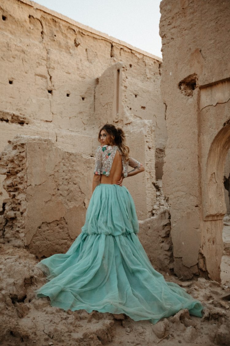 a bold bridal look with a crop embellished top with short sleeves and a mint-colored wedding skirt with a train